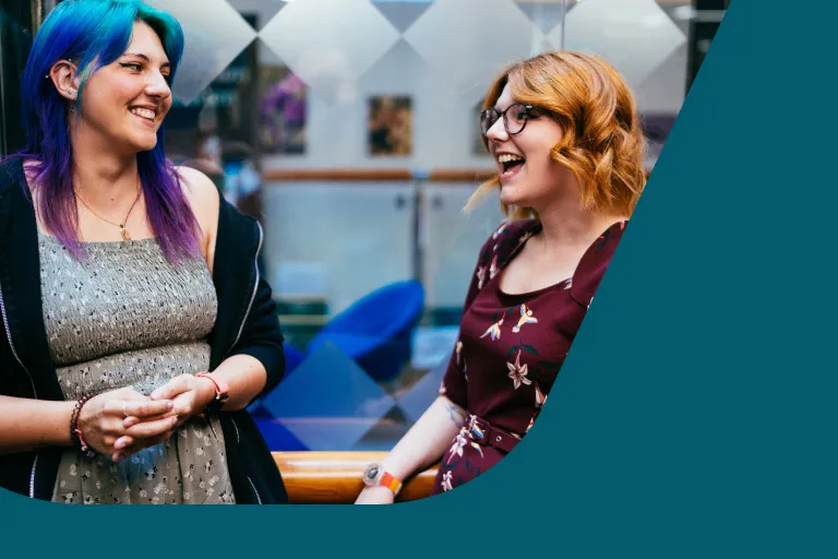 Two digital and data colleagues share a moment in a breakout space
