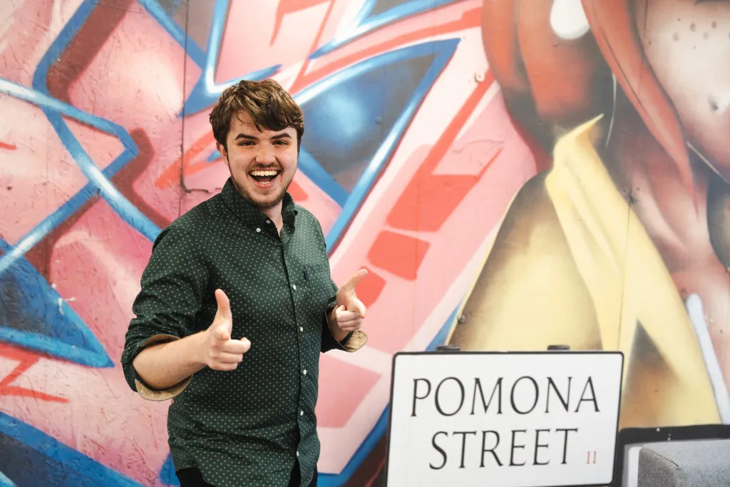 Bright, excited young person in front of a mural in the Aviva office