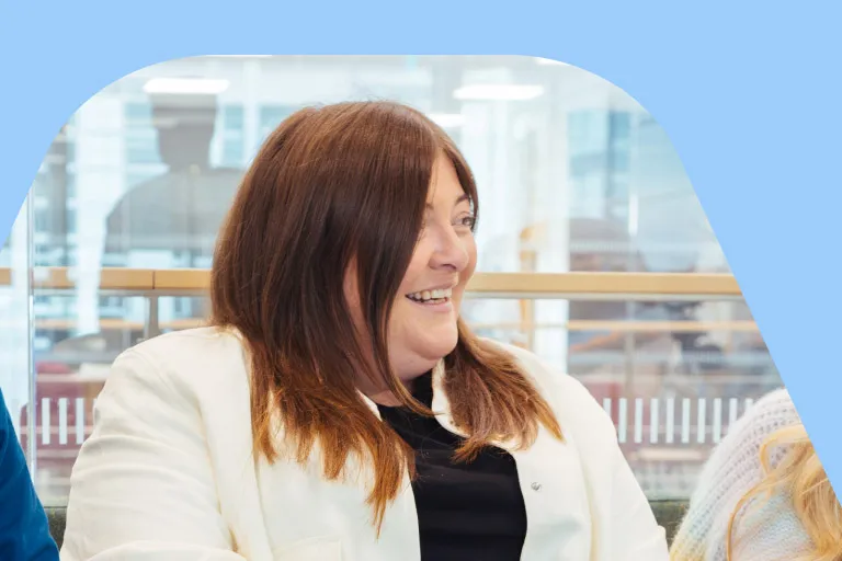Three colleagues sitting together on a sofa in an office setting, engaging in relaxed conversation