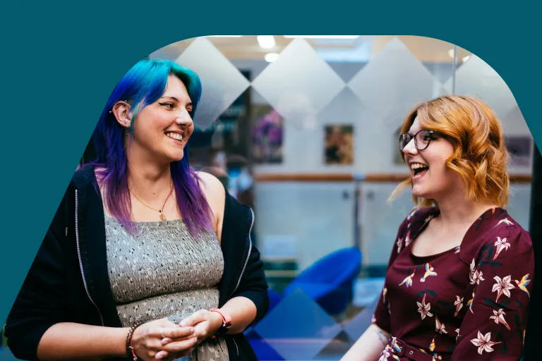Two digital and data colleagues share a moment in a breakout space