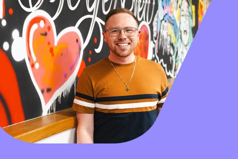 Smiling Man in Glasses in Front of Colourful Mural