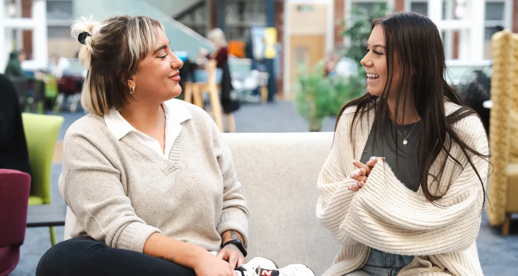 Two customer service and claims team members share a moment on a sofa