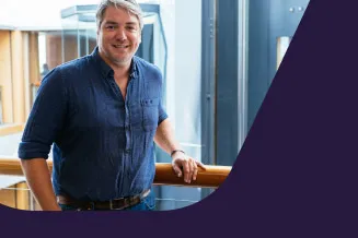 A male employee looks to camera and smiles by the office lifts