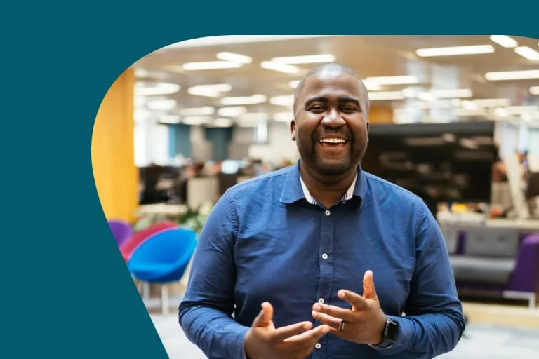 Smiling Black Man Wearing Blue Button up Shirt Stood in Modern Office