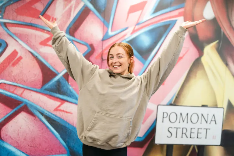 A young person in front of a colourful mural in the Aviva office