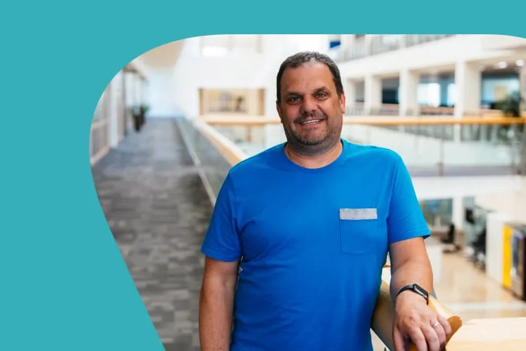 Smiling Middle Aged Man in Blue Tshirt Leaning Against Railing